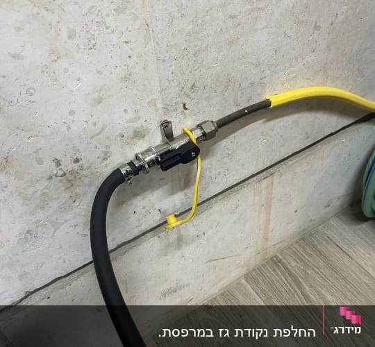 צינור גז שחור וצהוב מחובר לשסתום על קיר